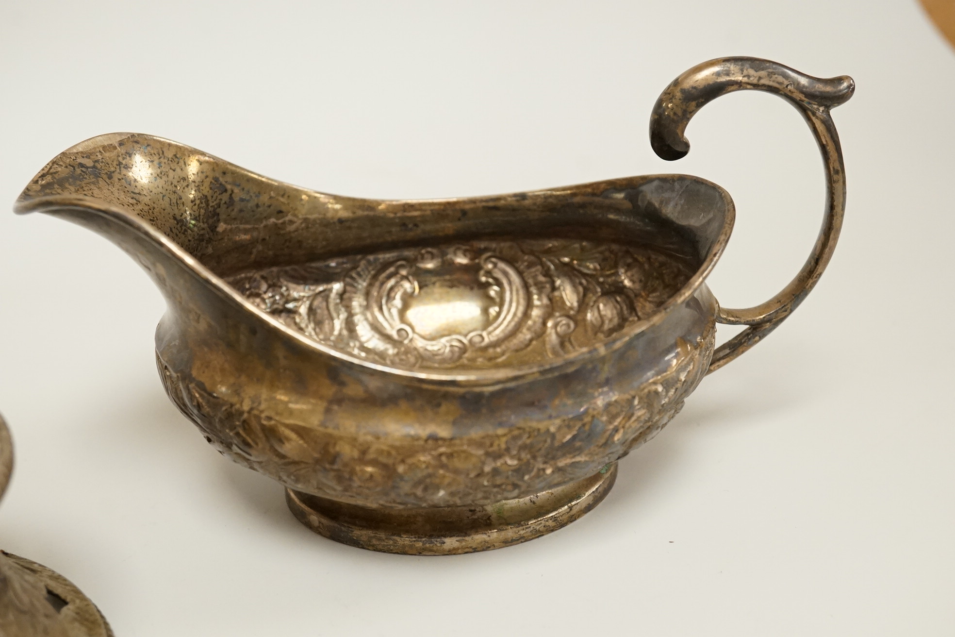 A late George III Irish embossed silver sauce boat, with flying scroll handle, maker. ?S, Dublin, 1817, length 14cm, together with a small Edwardian silver dish ring, I S Greenberg & Co, Birmingham, 1901, 7.2oz.